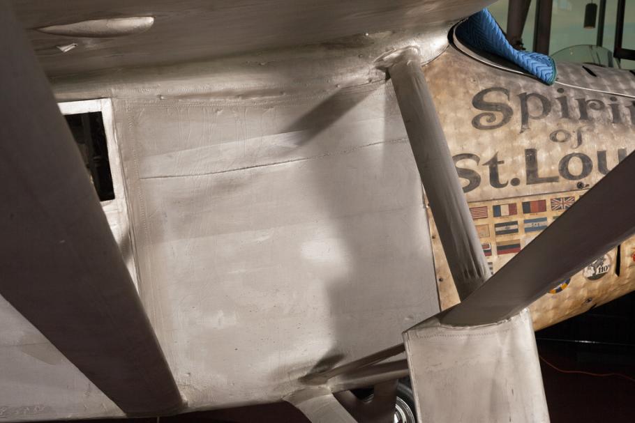 Close-up view of a side of the section below the cockpit of the Spirit of St. Louis, a silver-colored monoplane.