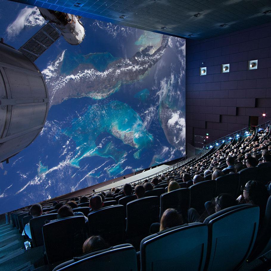 Shot of an IMAX movie screen with viewers seated in the theater. 