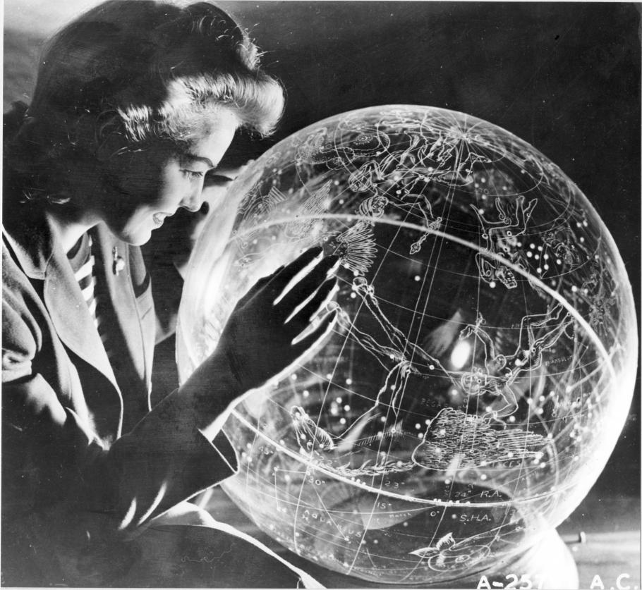 Black and white photo of woman staring into a clear globe. 