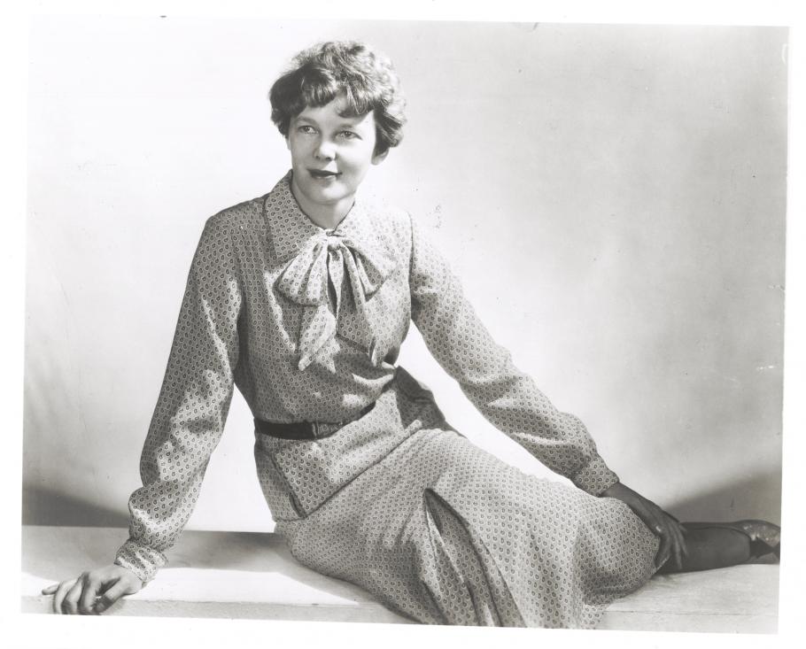 Amelia Earhart sits with her legs to the side. 