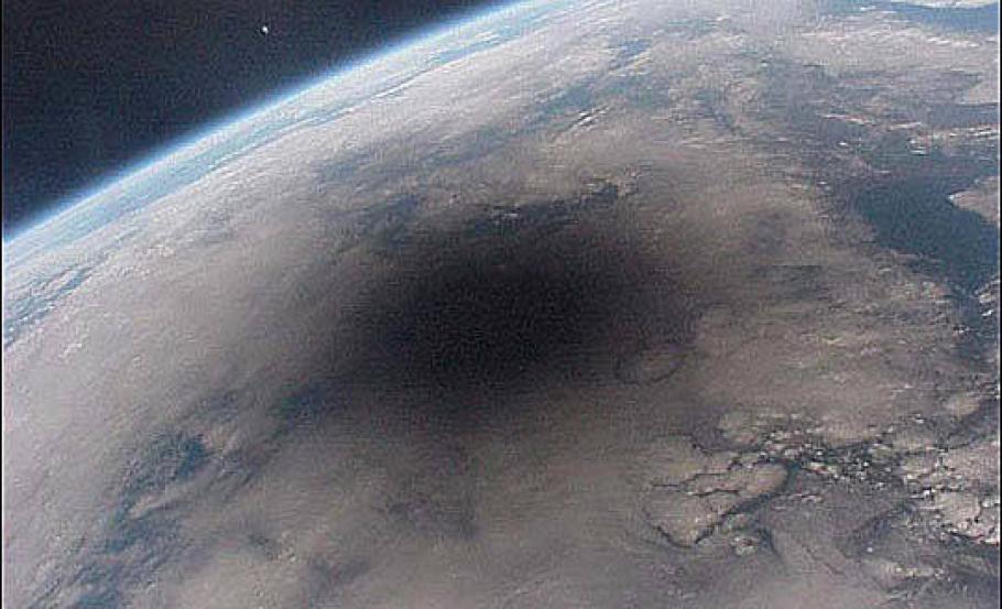 Image of Earth with a dark circle where the Moon is casting a shadow. 