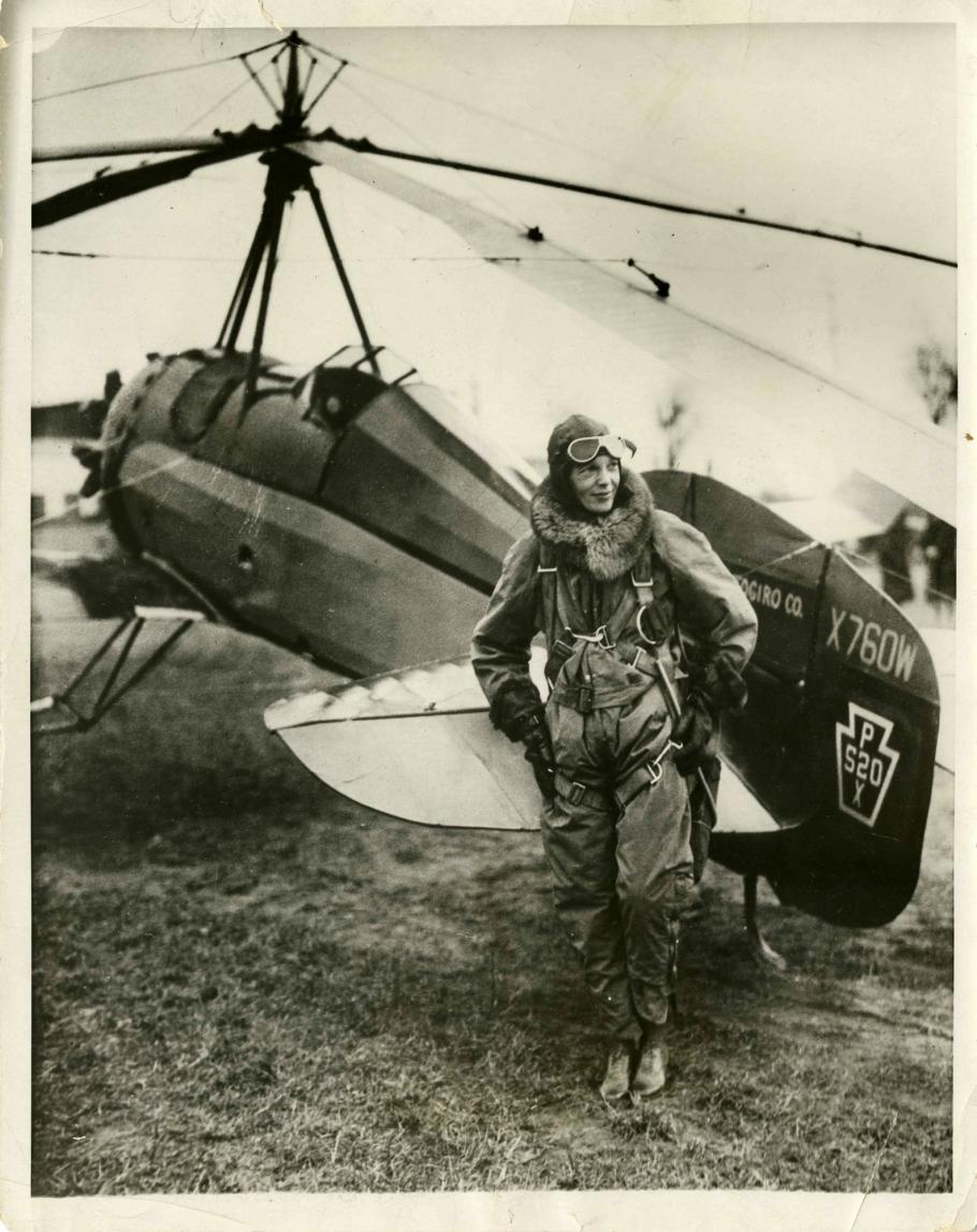 black and white photo of Amelia Earhart in front of an aircraft. 