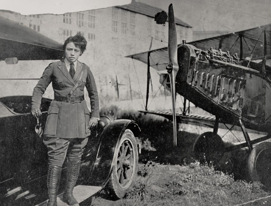 Bessie Coleman standing next to a car and airplane
