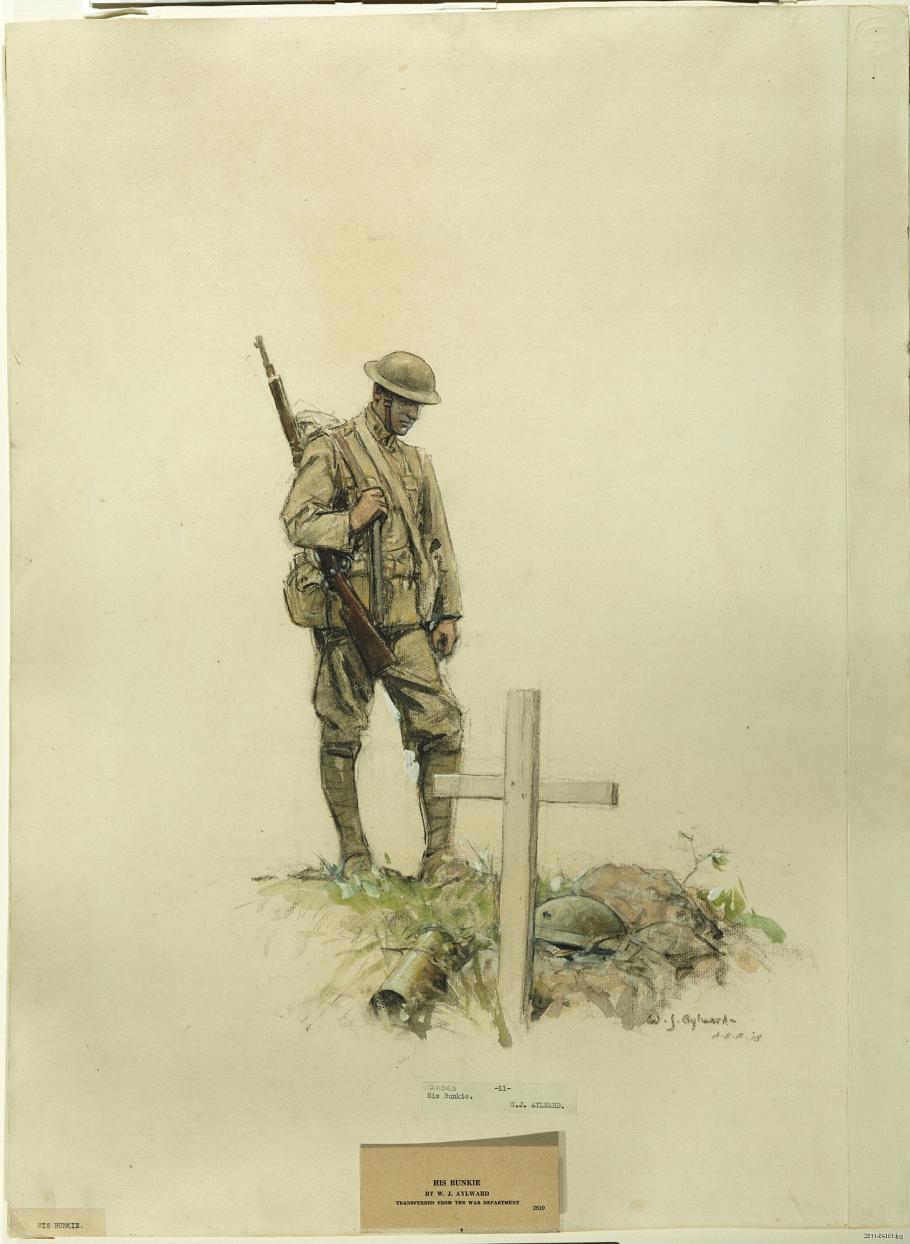 Soldier stands over a grave. 