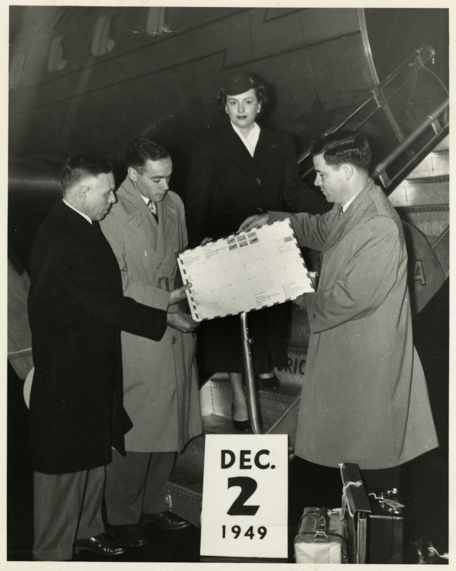 Three men and a woman in front of a Pan Am airplane