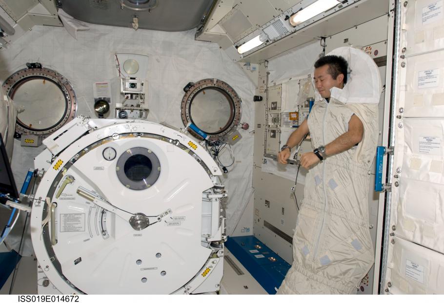 Astronaut is strapped into sleeping bed.