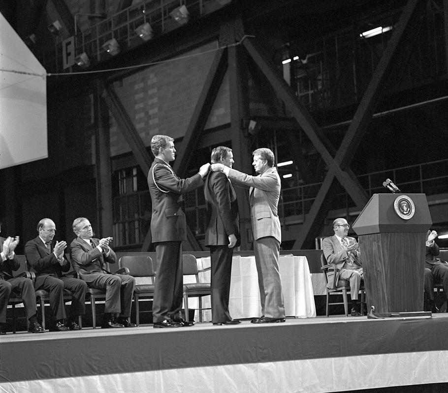 Jimmy Carter putting a medal around the neck of Neil Armstrong