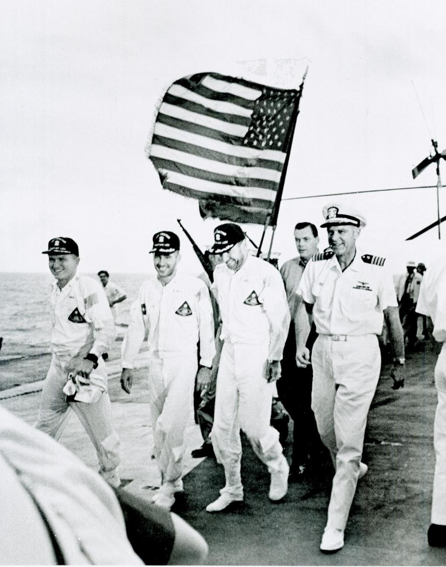 Apollo 8 astronauts and commanding officer of the recovery ship U.S.S. Yorktown walk the red carpet of the flight deck after splashdown recovery in the Pacific Ocean