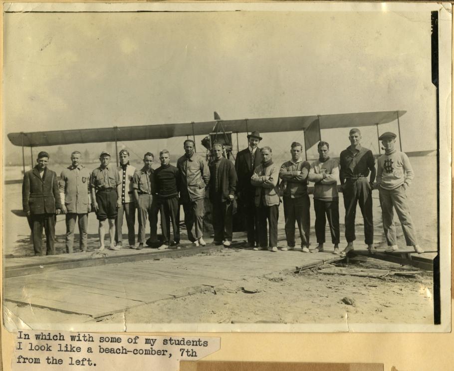 Fourteen men stand in front of an airplane