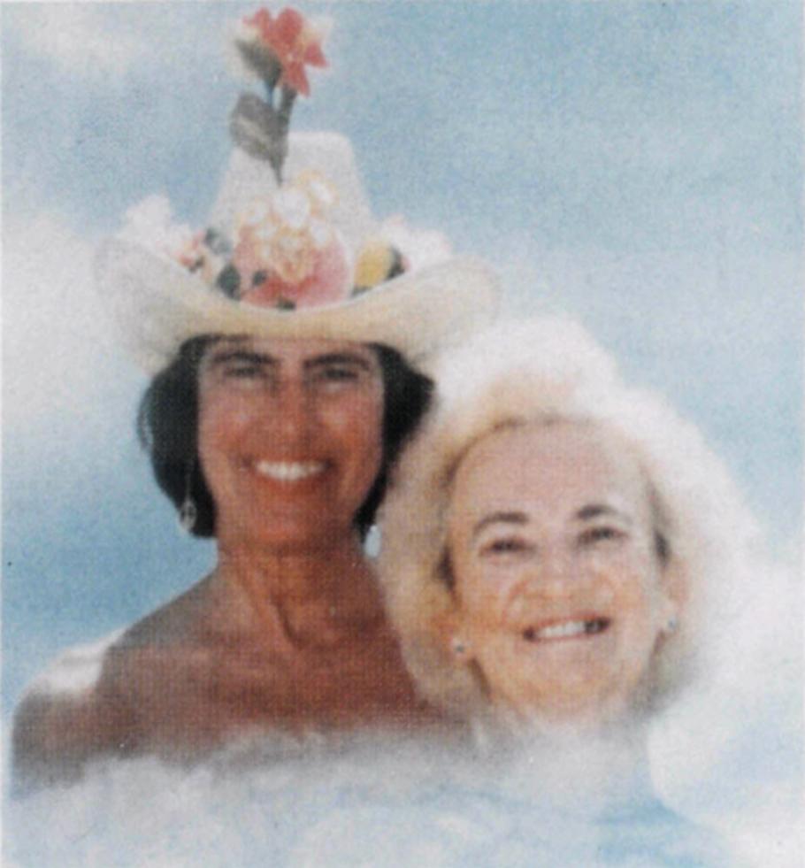 Two women in stylized clouds: Woman on the right has dark hair and is wearing a white cowboy hat with flowers sitting on the brim and pink hibiscus sticking out. Woman on right has white hair.