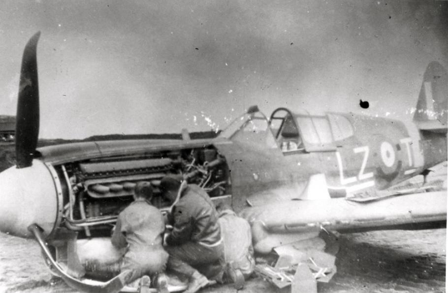 A photo of mechanics repairing damage to the belly of Kittyhawk IA 875, 1942.
