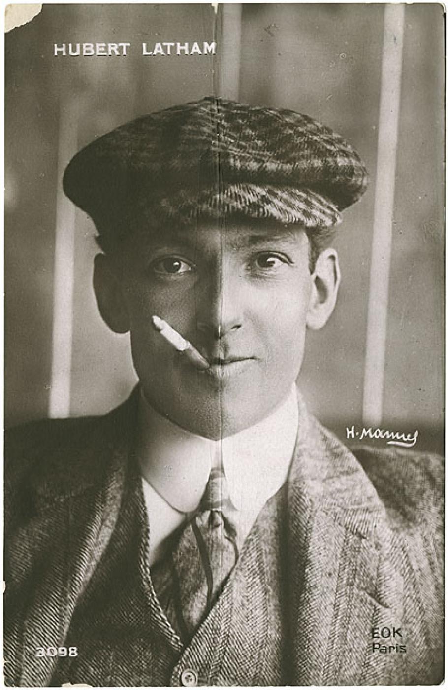 Black and white portrait of Latham with a cigarette in his mouth and a slight smile.