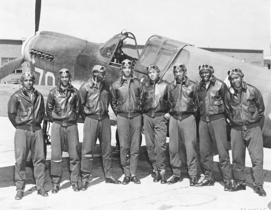 Eight men in jackets and aviation goggles in front of aircraft