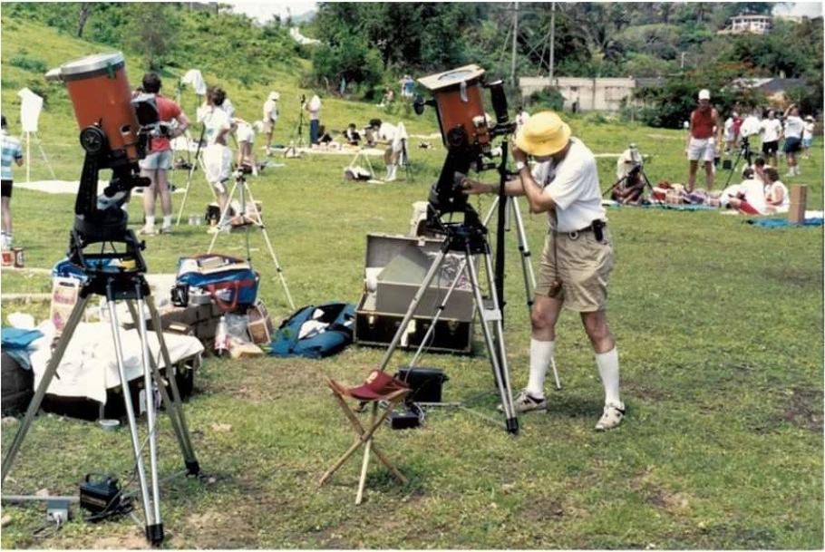 Man peers into a telescope at a large field. 
