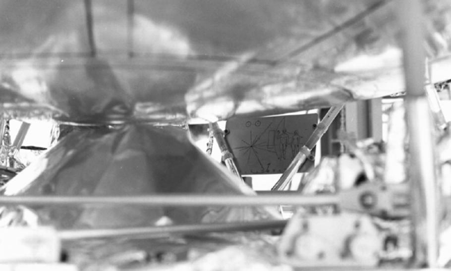 A black and white image of a spacecraft with a small rectangular plaque stuck inside. 