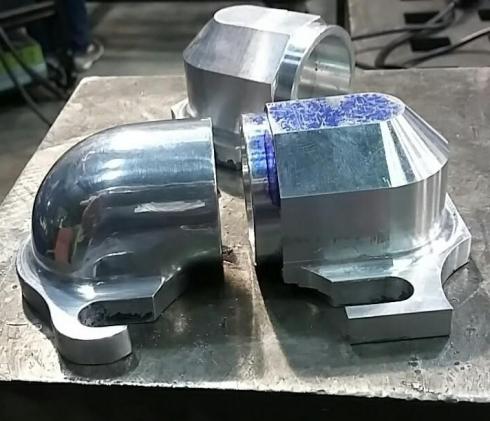 One rough milled aluminum elbow (left) in contrast to one hand shaped and polished elbow (right).