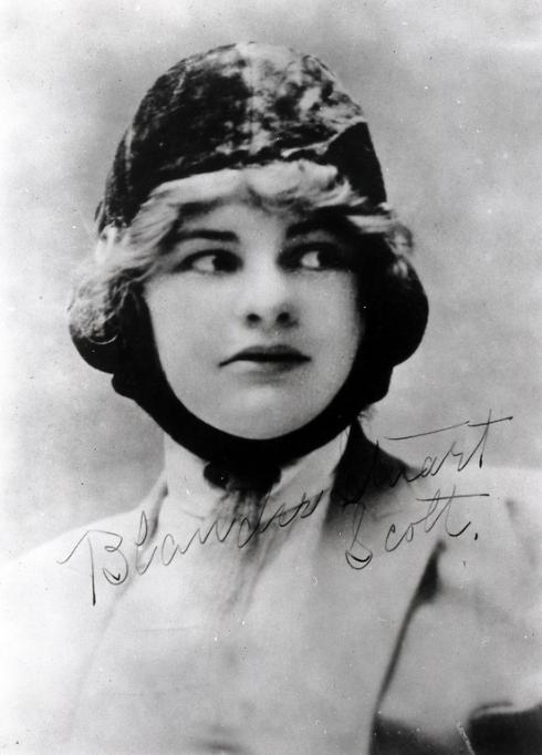 A women in a pilot's cap looks to the right. 