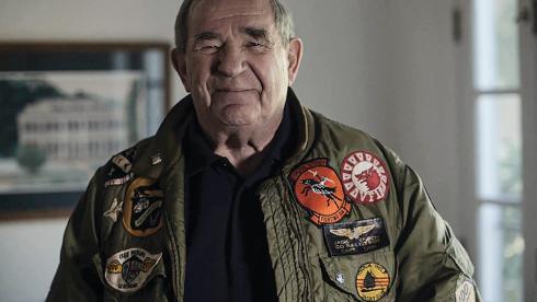 Jack Ensch wears a flight jacket covered in patches. He spent seven months as a POW in Vietnam after being shot down while flying an F-4B during a combat patrol.