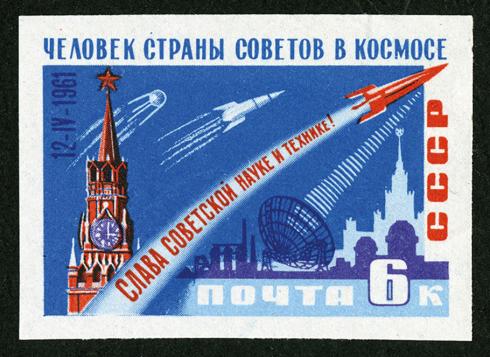 A Russian stamp in red, white, and blue depicts one satellite and two rockets in midair. The stamp is marked by words spelled in the Cyrillic alphabet.