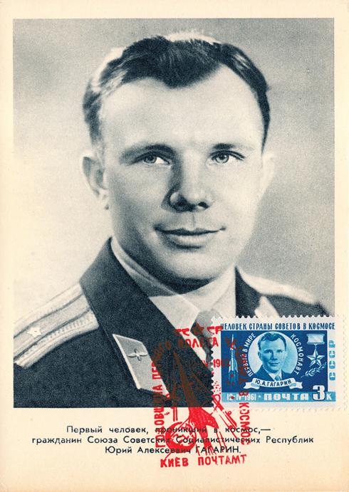 A postcard features a black-and-white portrait of a Russian man in his 20s wearing a military uniform. The postcard has a blue-and-white stamp with a red cancellation mark.