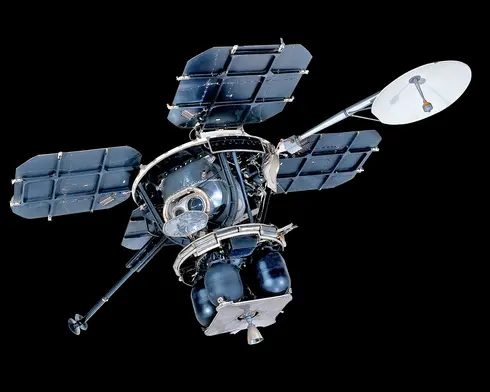 Four square solar panels constructed of aluminum frames and composite solar collectors, attached to a central body via aluminum struts. The Central bus consists of a variety of solid boxes and stalks with panels and other objects projecting from it. A tubular mast at the apex of the frame supports a rectangular a circular high gain antenna. A selection of instrument boxes, vernier rockets and their fuel containers, and the TV camera are attached to the frame.
