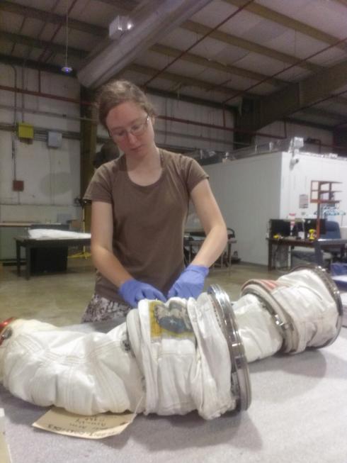 A white female Museum intern builds part of a spacesuit.