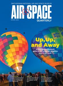 The cover of Air & Space Quarterly Magazine's Spring edition advertises the main story "Up, Up, and Away" with the description "In New Mexico, thoughts gather for the largest hot air balloon event in the world." Behind the text, two multi-colored hot air balloons are inflated and poised for launch against a twilight blue sky. Thousands of spectators are visible on the ground. Four other balloons have already ascended, appearing as dark spheres high above the scene.