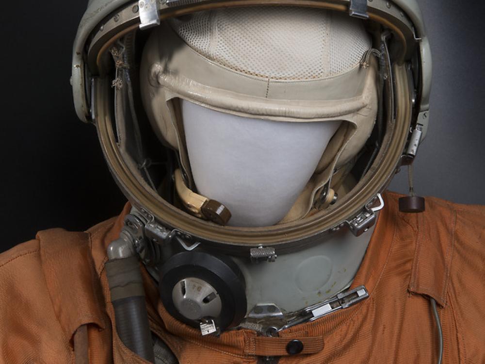 A helmet with CCCP on it, on a mannequin in a white suit.