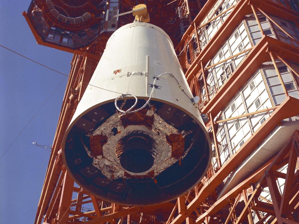 A color photograph of the Saturn Lunar Module (LM) Adapter being hoisted into position.