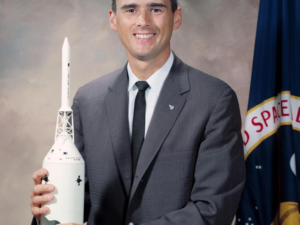 A color photographed portrait of Roger B. Chaffee holding a model of a rocket.