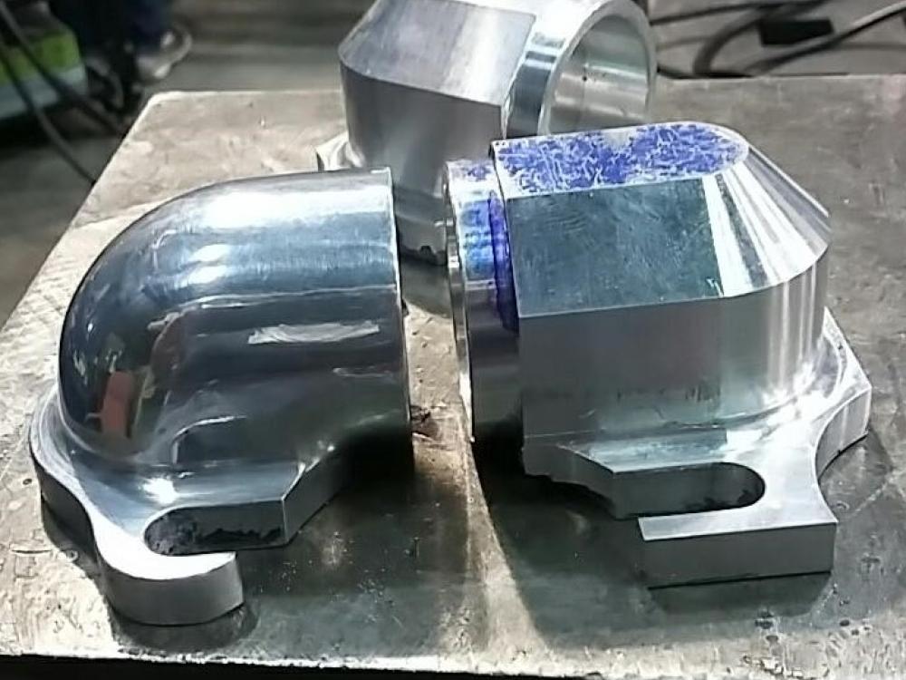 One rough milled aluminum elbow (left) in contrast to one hand shaped and polished elbow (right).