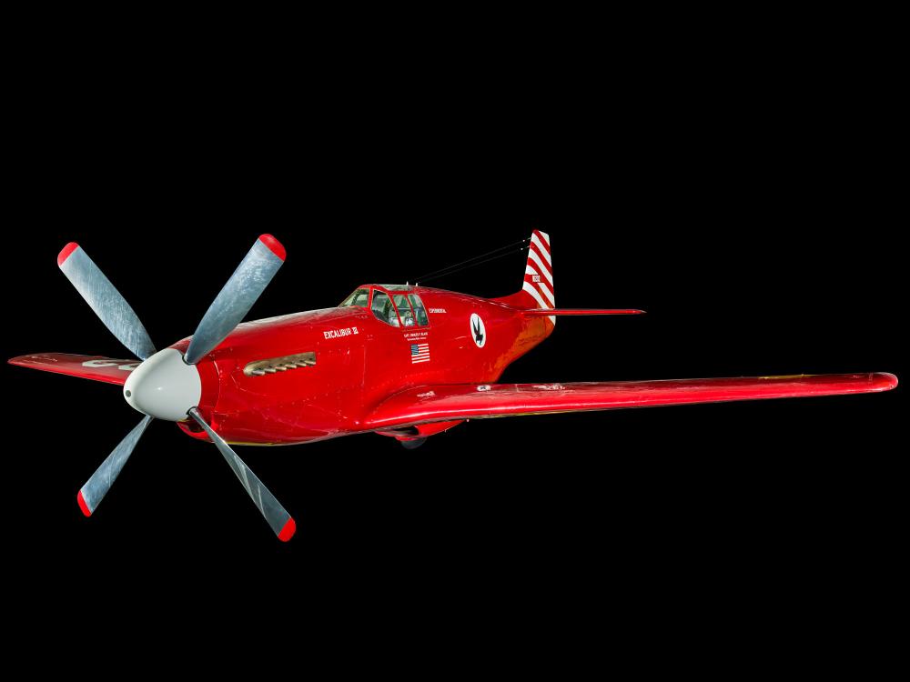 View of a red and white plane. Painted below the cockpit is the American flag.