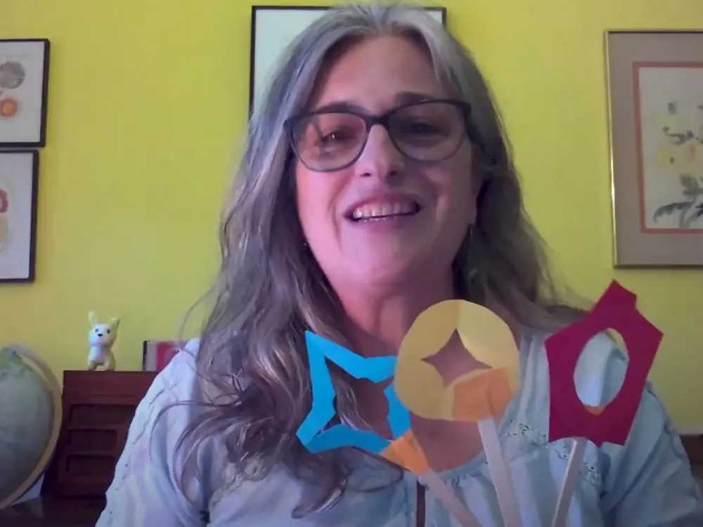 A woman holds up three shadow puppets. 