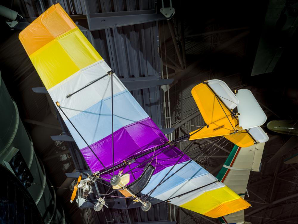 View of the undercarriage of a glider. The wing fabric is multi-colored.