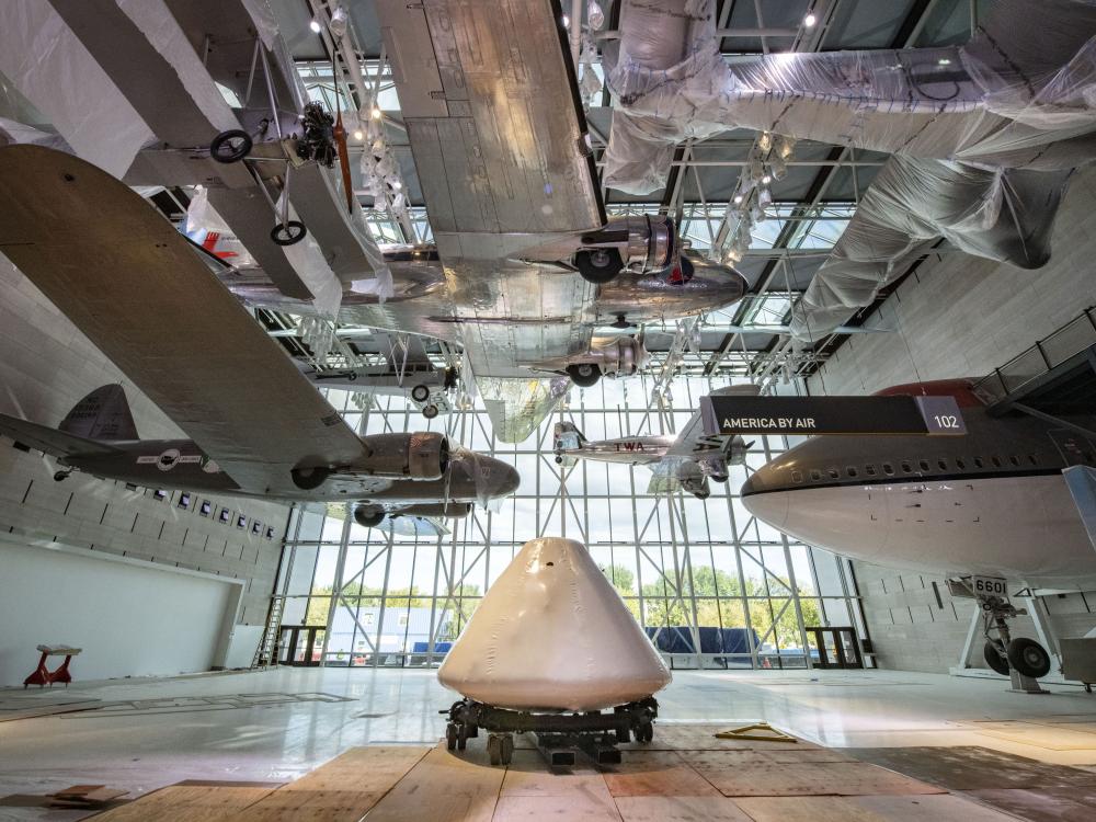 Command module Columbia sits in the middle of a museum gallery and surrounded by exhibits.