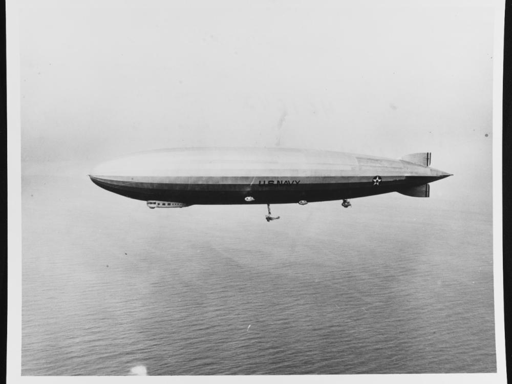 An airship is seen flying above the ocean.