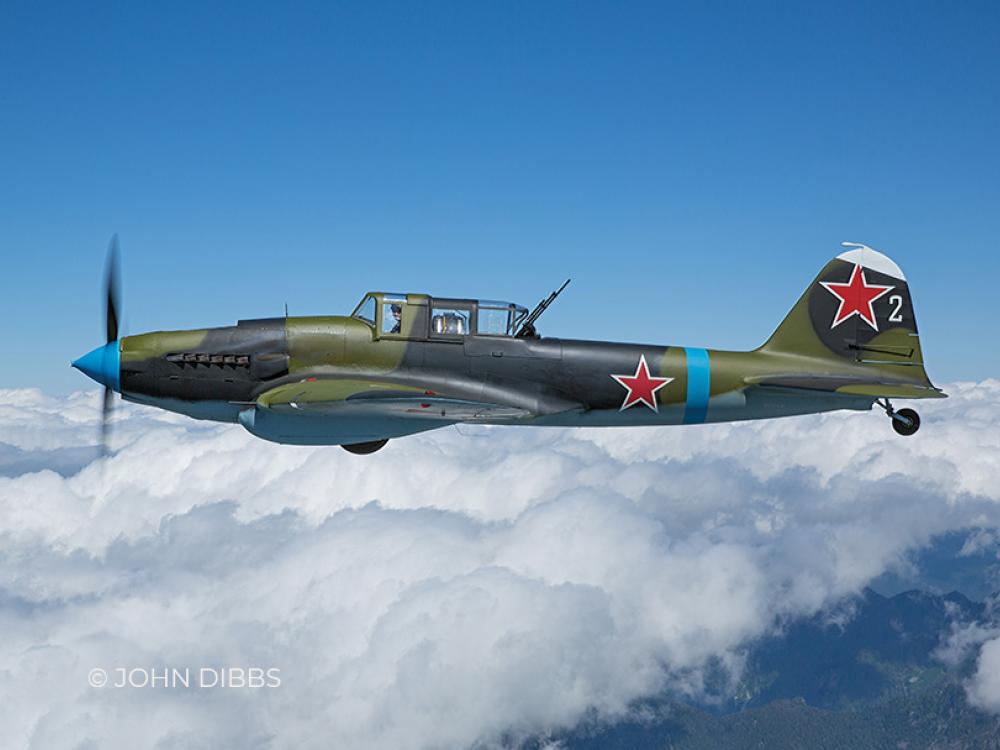 A restored IL-2 flies above the clouds, with a Soviet red star prominently painted on its side.