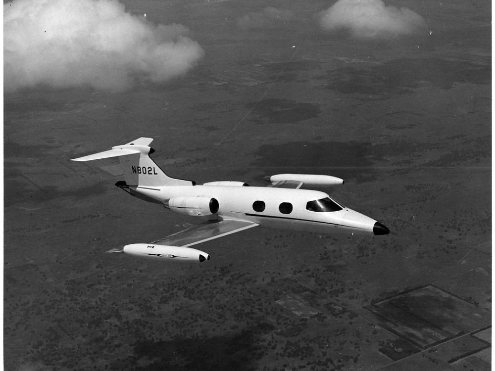 A side view of a small and sleek looking aircraft in flight, as if taken from the window of a nearby aircraft.