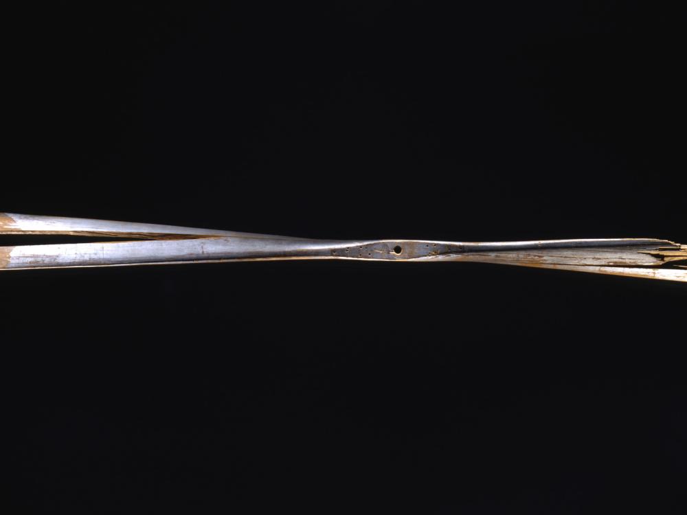 A wooden propeller against a black background. The right side of the propeller is very damaged, and the entire propeller has a split through it.