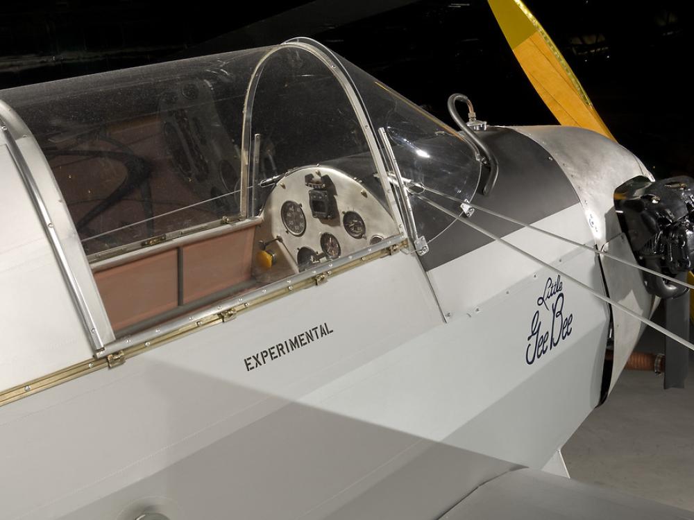 A side view of front half of a gray colored prop plane. Written under the cockpit window is "experimental."