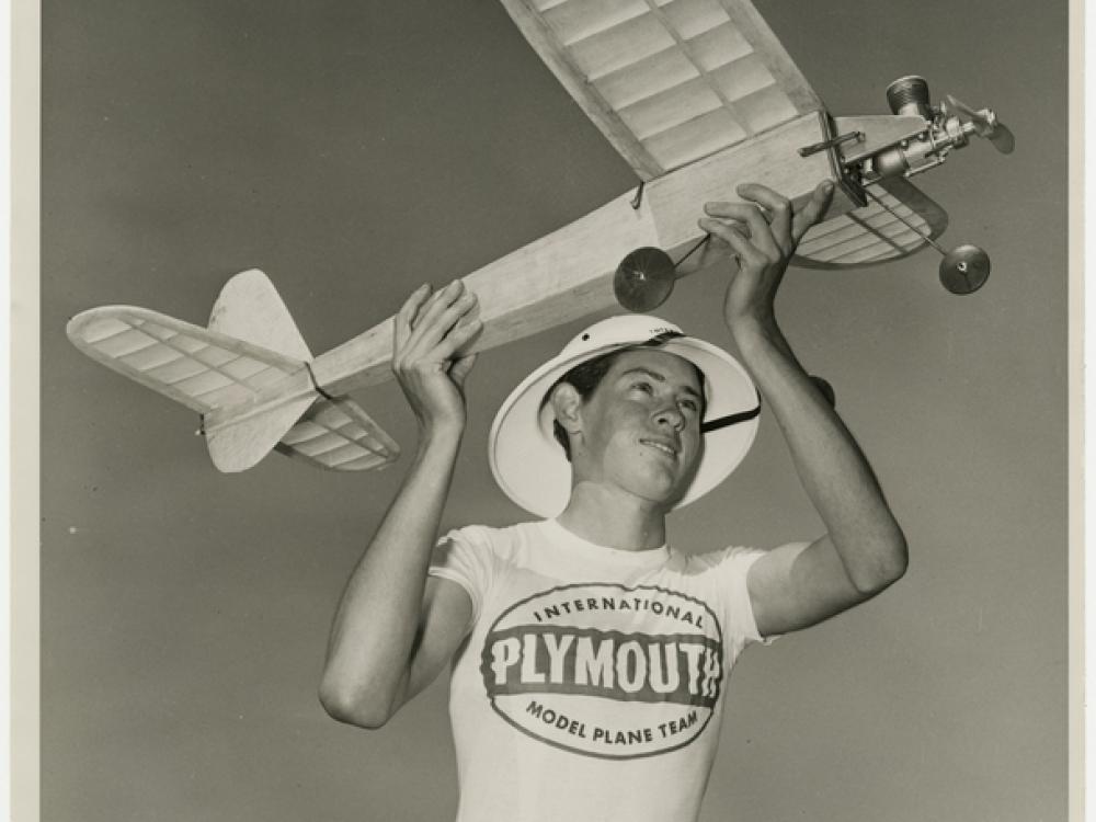 A teenaged-looking boy holds up a large model airplane as if he is about to launch it into the air.