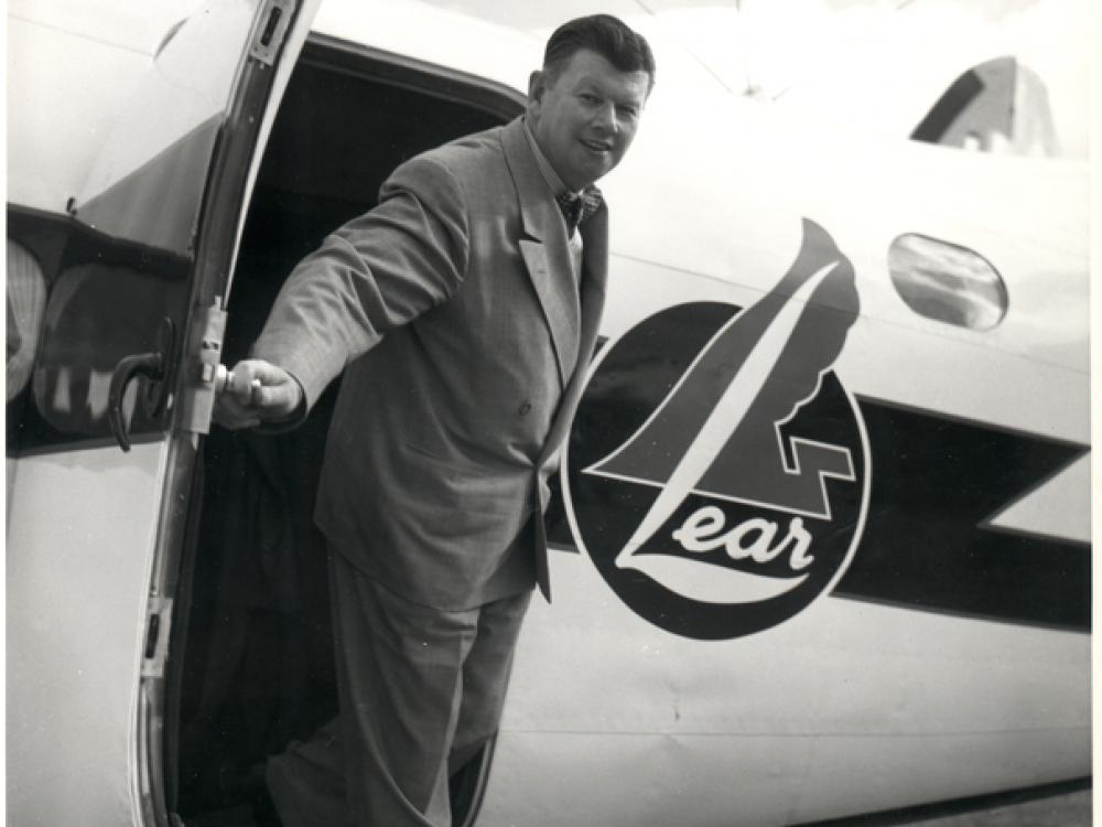 A man stepping out of the door of a small aircraft that says "lear" on its side.