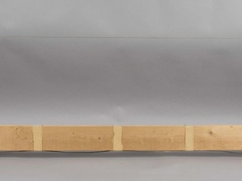 A piece of wood with two metal poles at each end. A wire is strung between the two poles, similar to a hack saw.