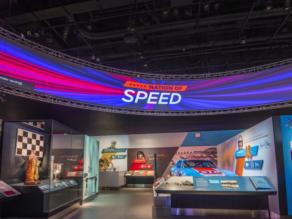 A view of Nation of Speed featuring a sign that reads "Nation of Speed" and a blue and red race car. 