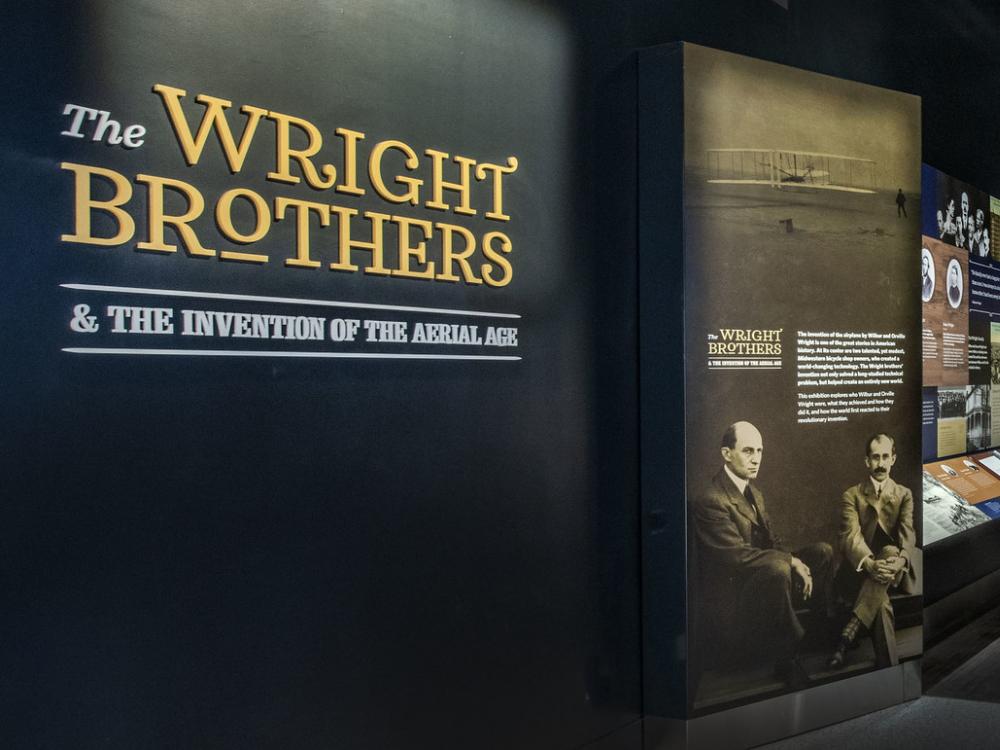 The entrance to Wright Brothers and the Invention of the Aerial Age, featuring information about them as printers and a sculpture of the two brothers. 