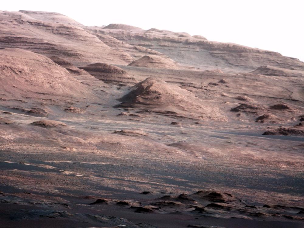 Jagged rocks on Mars jut out of the ground, each demonstrating their layered history through different bands of colors.