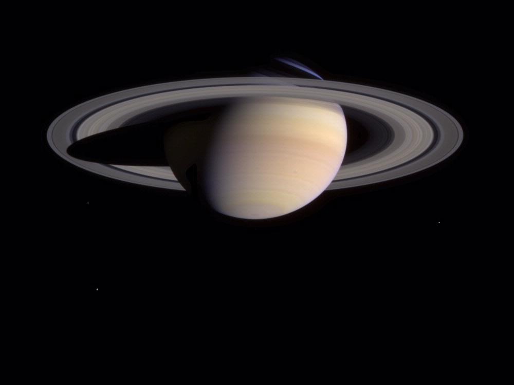 Saturn as seen from the bottom half up. A spot can be seen on the bottom left of the planet.