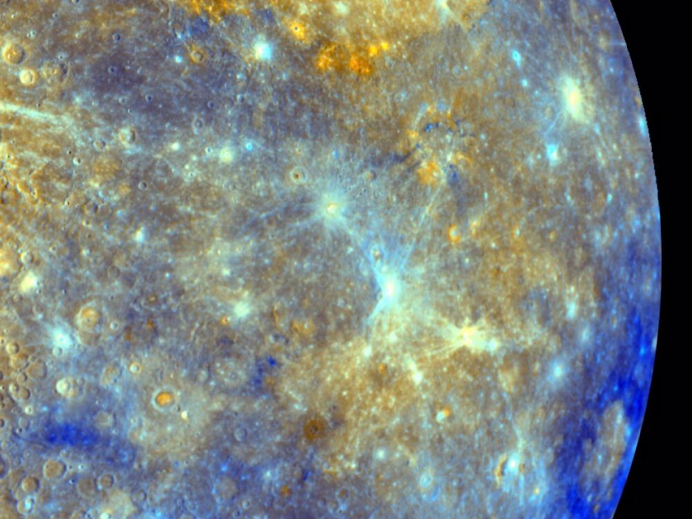 An image showing a half circle view of Mercury's surface in purples and yellows. 