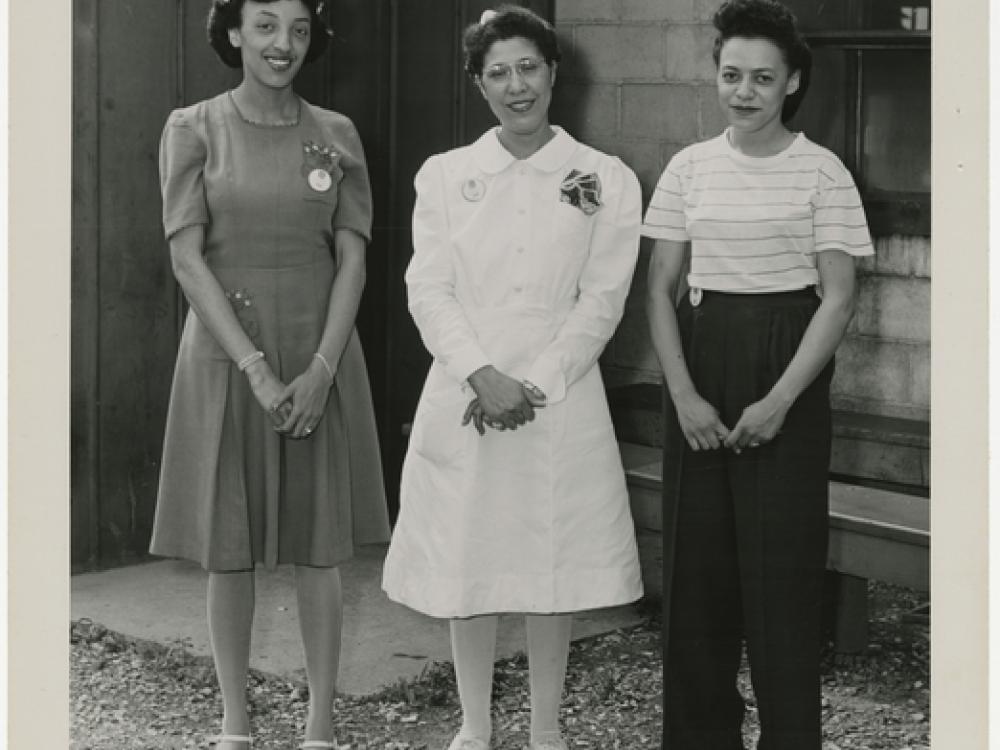 Three women stand outside a building