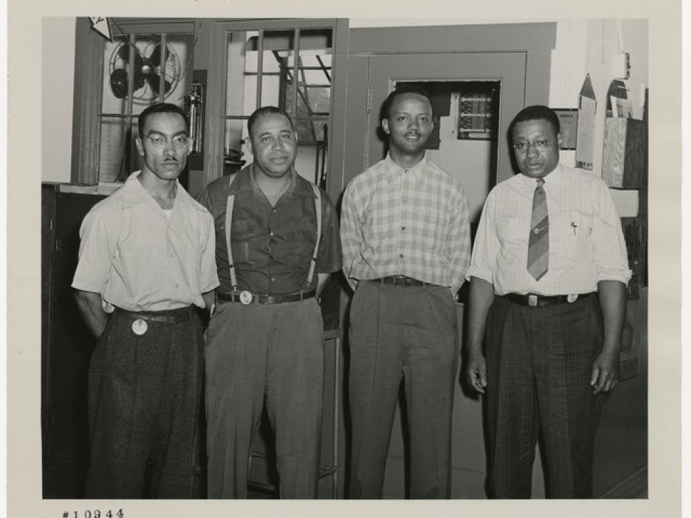 Four men stand inside an industrial building